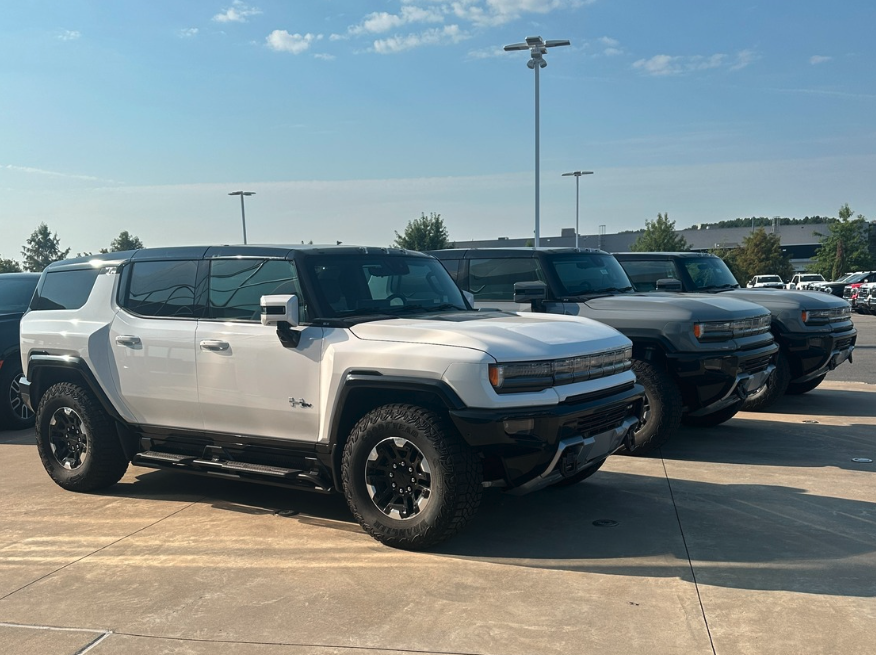 Row of GMC Hummer EV SUVs in white and gray parked at Crain Buick GMC in Conway, Arkansas under clear fall skies